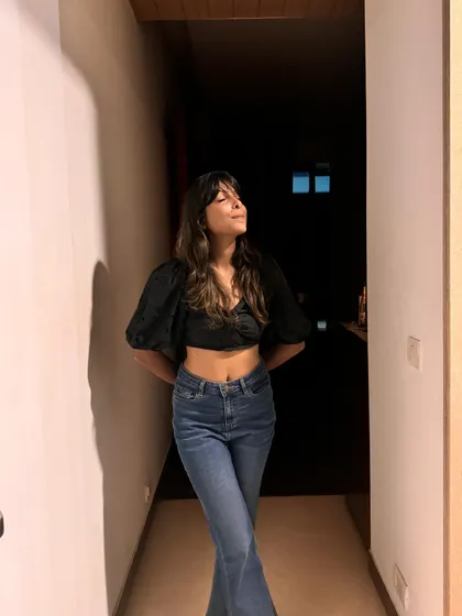 A simple yet chic evening look. A black crop top with puff sleeves paired with high-waisted flare jeans creates a flattering and stylish silhouette.