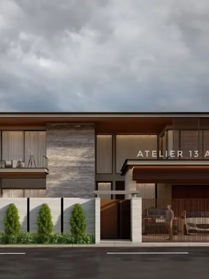 A view of the modern villa from the street, highlighting the private entrance and carport. The facade combines textured stone panels with warm wood accents and a cantilevered upper floor, creating a dynamic composition that is both welcoming and secure.