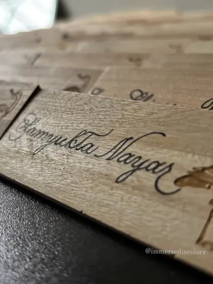 A close-up of a wooden name plate, showing the texture of the wood grain beneath the smooth calligraphy. Working on natural materials like this adds a warm, organic feel to event decor.