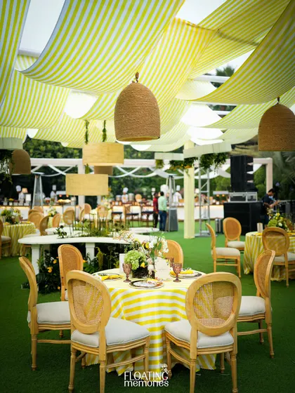 The elegant guest seating arrangement, with striped tablecloths and natural wood caned chairs, perfectly complements the sunny, garden-party vibe of this luxury baby shower.
