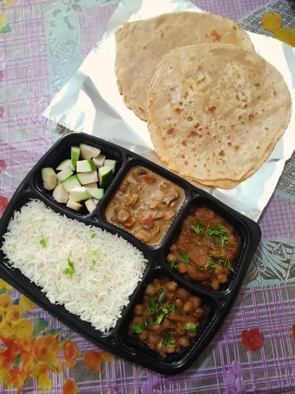 A satisfying North Indian thali with two plain parathas, rich mushroom masala, homestyle chole, plain rice, and fresh guava slices for a complete lunch or dinner.