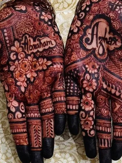 A close-up of the groom's name, "Abraham," beautifully written into the bride's palm. The dark stain makes the personalized element stand out even more.