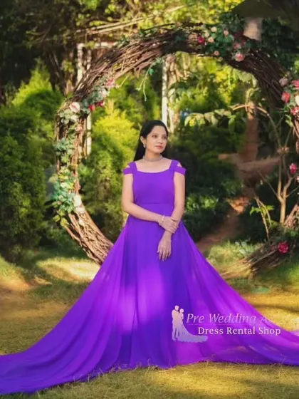 A full view of our solid purple trail gown, spread out in a garden setting. The off-shoulder neckline and the sheer volume of the fabric create a regal, princess-like effect.