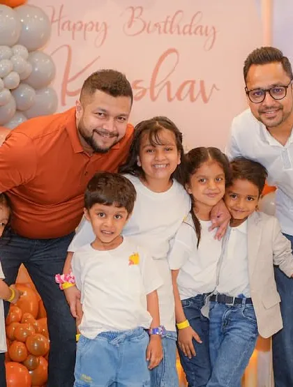 A group of friends and family pose for a photo at a pumpkin-themed party.