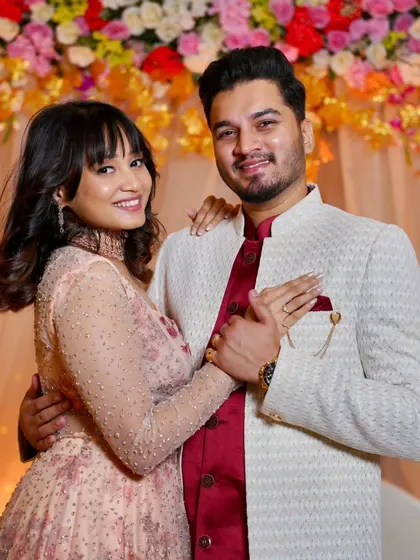 The happy couple showing off the ring. Her makeup is a lovely mix of peach and pink tones, perfect for her engagement outfit.