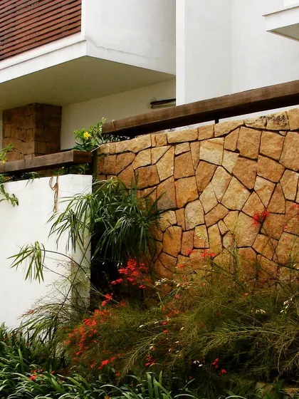 Another example of a natural stone compound wall, where the irregular shapes and warm tones of the stone create a beautiful contrast with the soft foliage. This is how we build with nature, not just in it.