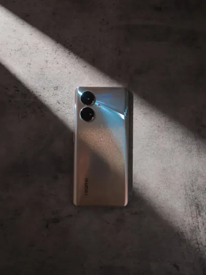 A minimalist shot of the realme 10 Pro+ 5G, using a single ray of light to highlight its glossy, reflective back.