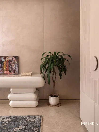 A close-up of a playfully sculptural console table. Paired with a simple potted plant, it adds character and a touch of modern art to this serene guest room corner.