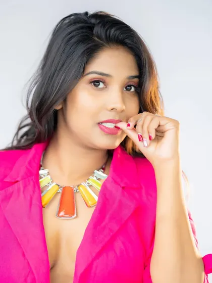 A pop of color. The bright pink blazer and chunky necklace make a bold statement in this clean, high-key studio portrait.