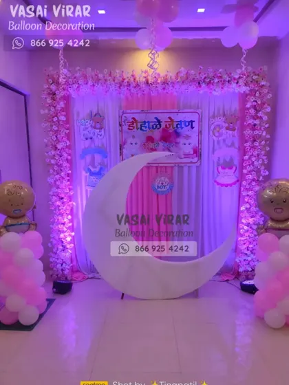 Here is the full view of the pink-themed Dohale Jevan decoration. The large white moon prop provides a unique and comfortable seating area for the mom-to-be, surrounded by balloon pillars and a floral backdrop.