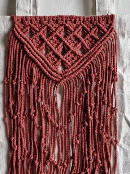 A full view of the macrame panel on the canvas tote bag. It adds a unique, handmade, and bohemian touch to a practical, everyday item.