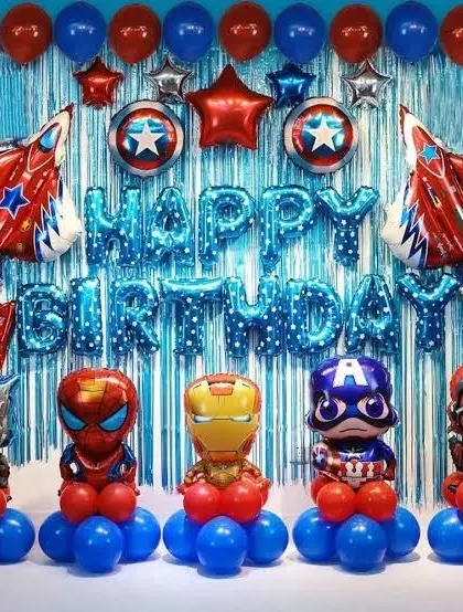 An action-packed Avengers birthday decoration. This setup includes a blue tinsel curtain backdrop, "Happy Birthday" foil letters, and balloon stands featuring the full team of superheroes like Iron Man, Captain America, and Spider-Man.