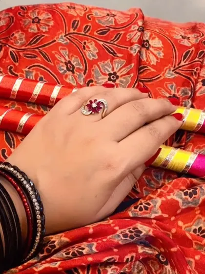 Festive details for Navratri. A hand adorned with black bangles and a statement ring holds colorful dandiya sticks, capturing the vibrant spirit of the festival.