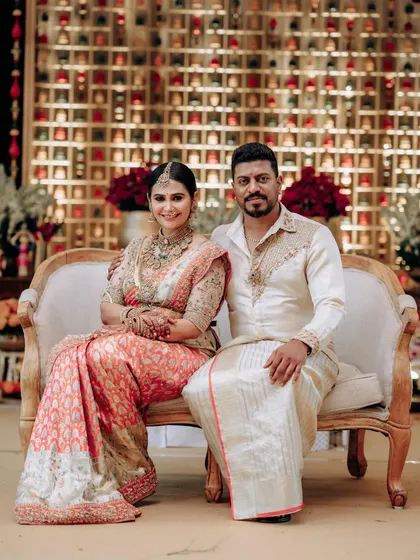 A formal portrait of a couple seated on a vintage sofa. Their coordinated outfits, designed by us, are perfect for creating lasting memories.