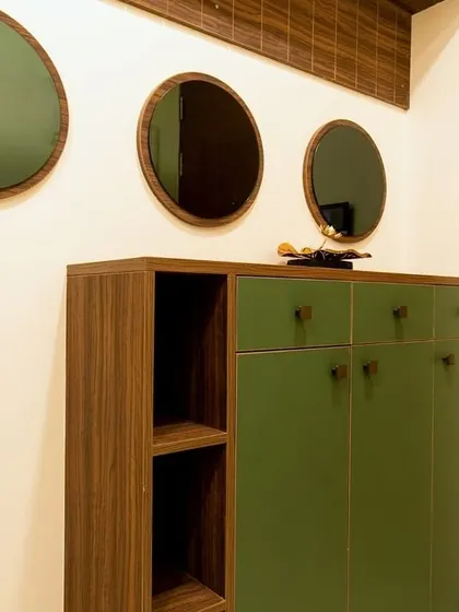 A functional and stylish entryway in the Murlis' home, featuring a green and wood shoe cabinet with open shelving and a trio of decorative round mirrors on the wall.
