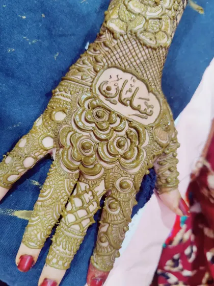 Hiding the groom's name in the bride's mehndi is a fun tradition. Here, the name 'Sultan' is beautifully written in Urdu script within the intricate design.
