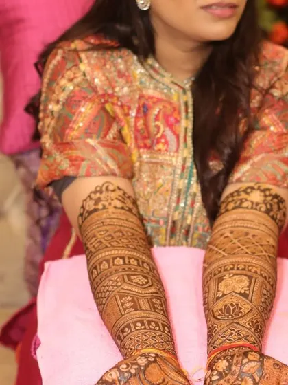 A bride showing her full-arm mehandi design. The patterns are dense and traditional, a style that many brides love for its classic and rich look.