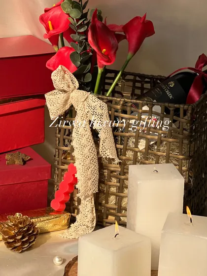 Wrap up joy and warmth this Christmas. This hamper, featuring red flowers, a bottle of wine, and white candles, creates a cozy and festive holiday vibe.