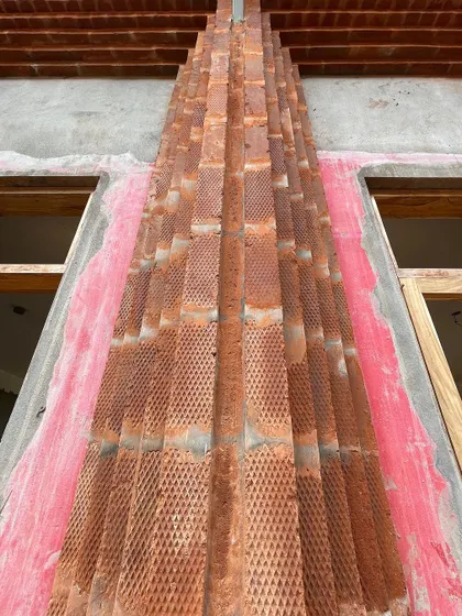 A close-up of the textured, half-cut bricks used for the framing detail. The craftsmanship involved in laying these bricks is evident.