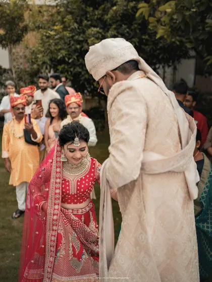 The groom leads his bride, a symbolic and beautiful moment in the wedding ceremony. The focus is on their connection amidst the crowd of loved ones.