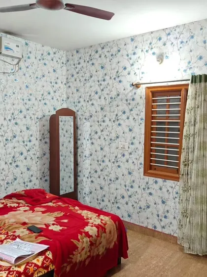 A bedroom with a blue floral vine wallpaper, creating a fresh and charming atmosphere.