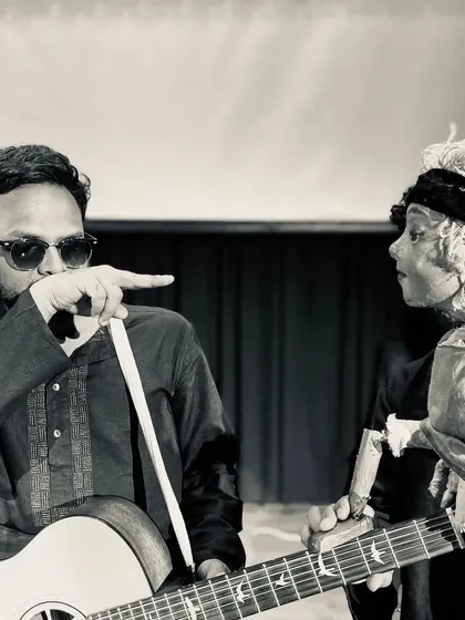 A playful, black-and-white shot of a musician and a puppet from the show. This captures the lighthearted and interactive spirit we bring to our performances.