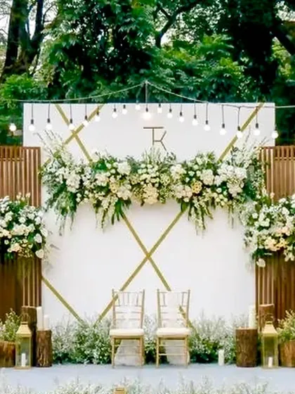 This rustic-chic reception backdrop features a monogrammed white panel accented with wooden slats and beautiful white floral arrangements. The warm Edison bulbs add a touch of vintage charm.