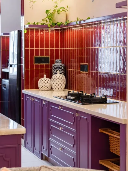 A detail shot of the Sakura kitchen, highlighting the texture of the red tiles and the custom-paneled purple cabinetry. The choice of unique decor pieces and careful placement of greenery adds another layer of curated charm.