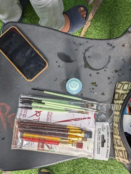 The artist's workspace. A simple setup with brushes, paints, and a phone for reference is all you need to start creating.
