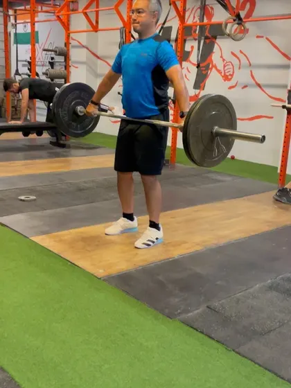 An athlete executing a hang snatch pull. This variation is excellent for teaching lifters to stay over the bar longer and use their legs to drive the weight up.