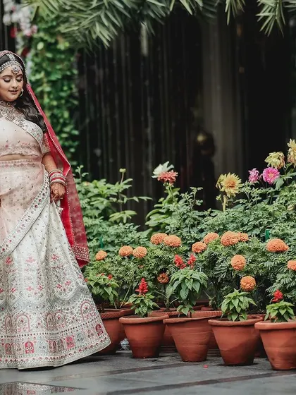 A lovely outdoor bridal portrait, with the bride standing among potted marigolds, adding a touch of natural color.