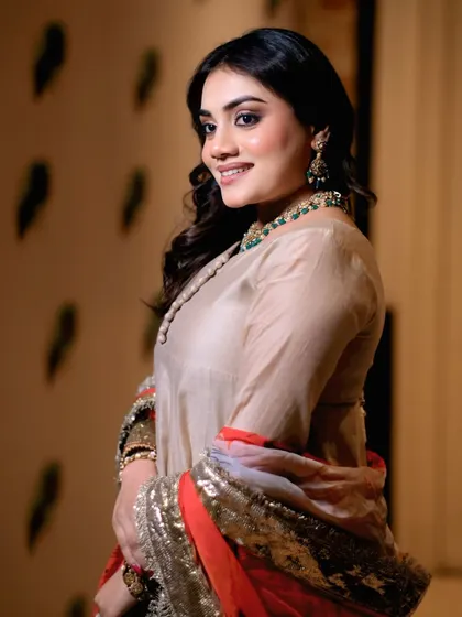 A graceful over-the-shoulder pose by a model. This angle highlights the outfit's sleeves and the model's elegant posture.