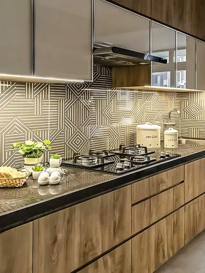 This kitchen features a striking geometric backsplash that complements the wood-grain cabinets and dark countertop.