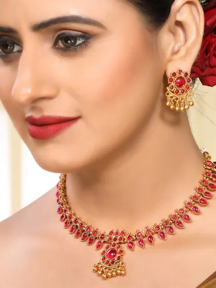 A close-up of a model wearing a ruby-studded traditional necklace, highlighting the vibrant color and detailed craftsmanship.
