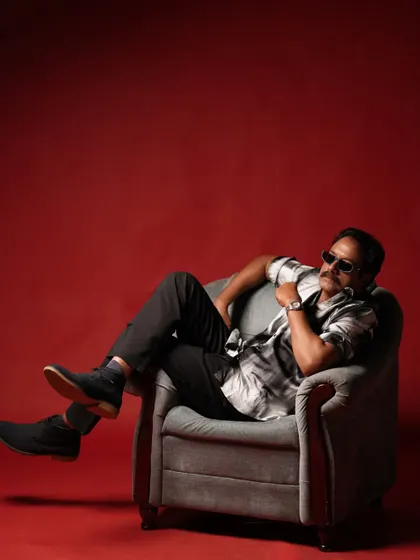 A cool, relaxed shot of an actor for a fashion editorial with Sol by LOC. The grooming was minimal and modern, focusing on a clean finish to complement the stylish outfit and red backdrop.
