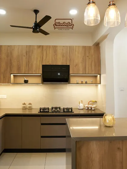 An island kitchen design where the island also serves as a breakfast counter. The pendant lights above the island add a stylish touch.