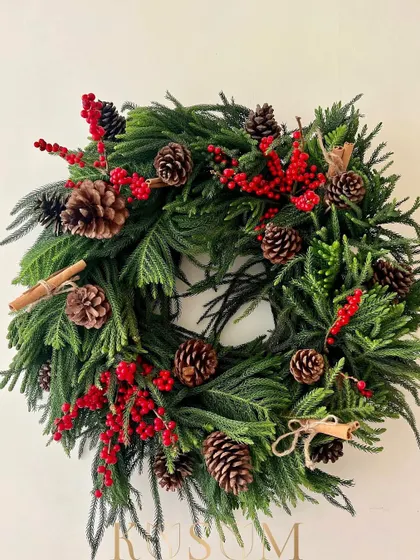 This wreath can be hung on a door to welcome guests with festive cheer. The combination of fragrant pine, spicy cinnamon, and bright berries captures the essence of Christmas.