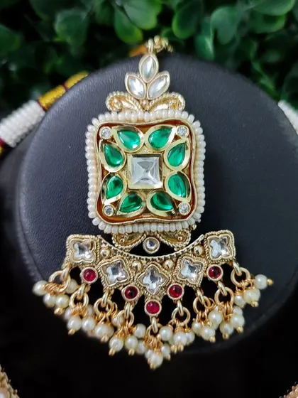 A close-up of the central pendant of the necklace, showing the detailed kundan work.