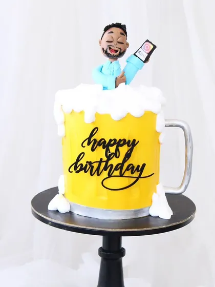 A fun beer mug-shaped cake perfect for a birthday toast. The cake is shaped and decorated to look like a frothy mug of beer, complete with a custom caricature of the birthday person.
