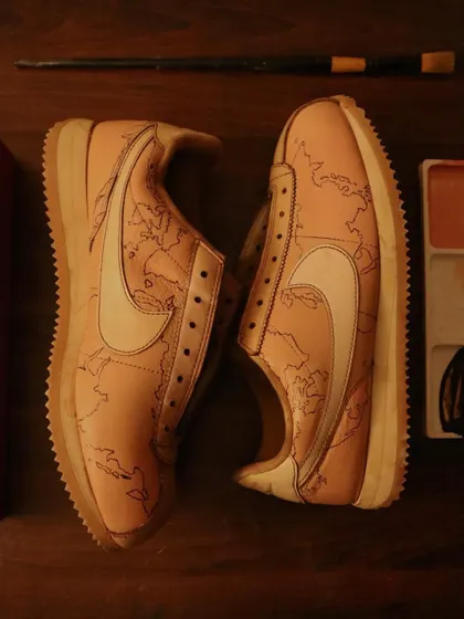 The first step to a masterpiece. This is a pair of Nike Cortez after being dyed in coffee, with the world map base carefully painted on. This clean canvas is ready for the final layers of personalized art.