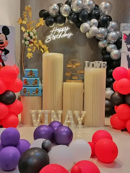 Another view of the cartoon-themed decor, showing the full setup with plinth stands and light-up letters for the name "VINAY".