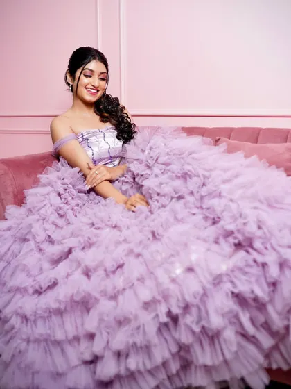 A full shot on the pink sofa, showing how the gown fills the frame with its beautiful ruffles.