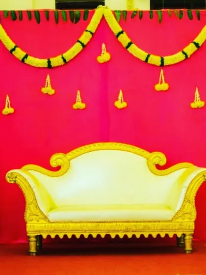 A vibrant pink backdrop framed with thick marigold garlands in a scalloped design. This simple yet striking setup provides a colorful background for photos at any celebration.