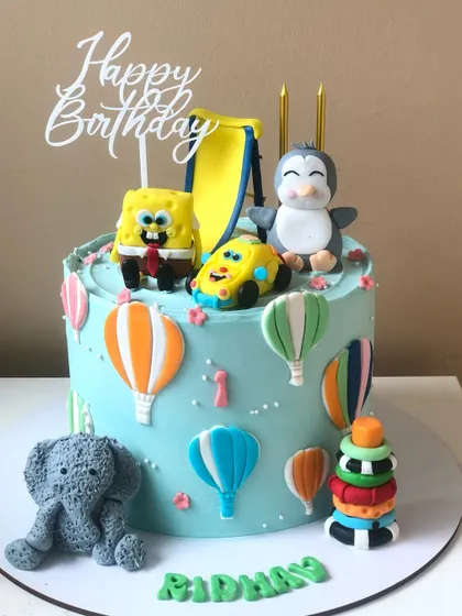 A cake featuring a collection of favorite toys, including Spongebob, a penguin, and an elephant, perfect for a little one's special day.