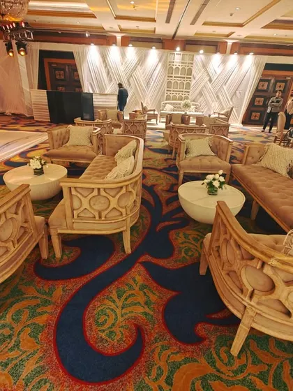 An expansive lounge area with multiple seating clusters. The unique, carved-wood sofas and armchairs are arranged to facilitate conversation, demonstrating our ability to furnish large spaces for networking events.