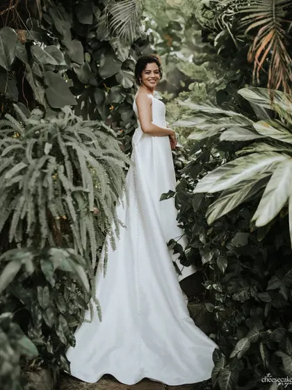 A stunning portrait of the bride in her white wedding gown, surrounded by lush greenery.