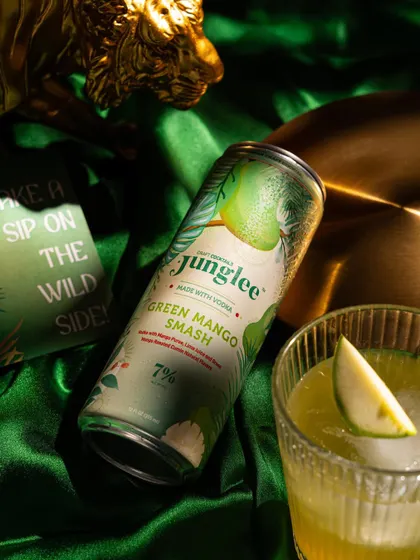 A moody and luxurious shot of a canned cocktail on a rich green, satin background.