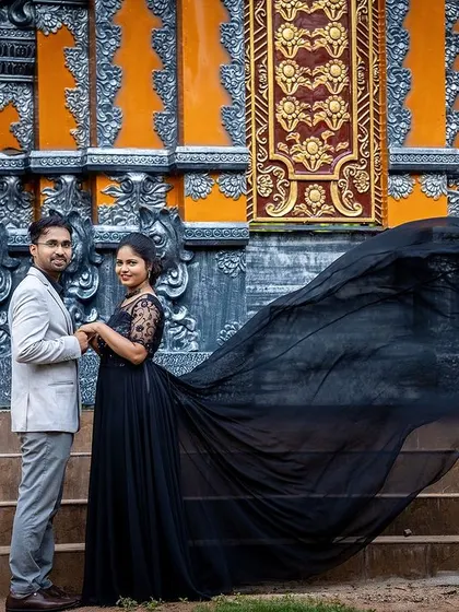 A dramatic pre-wedding shot featuring a long, flowing dress against a backdrop of intricate architecture.