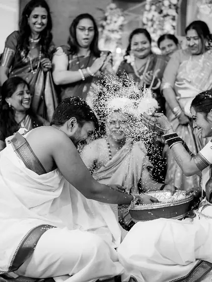 The 'Talambralu' ritual, where the couple showers each other with rice, captured in a dynamic black and white frame that freezes the joy and motion.
