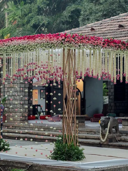 A closer look at the pink and white floral mandap, highlighting the intricate details of the hanging garlands and the elegant structure. The design creates a perfect blend of modern romance and traditional charm.